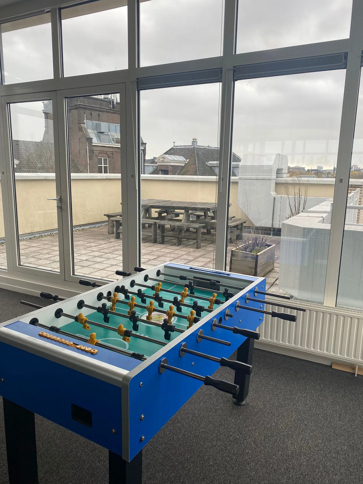 Tafelvoetbaltafel in een kantoorruimte met uitzicht op een dakterras aan de Prins Hendrikkade.